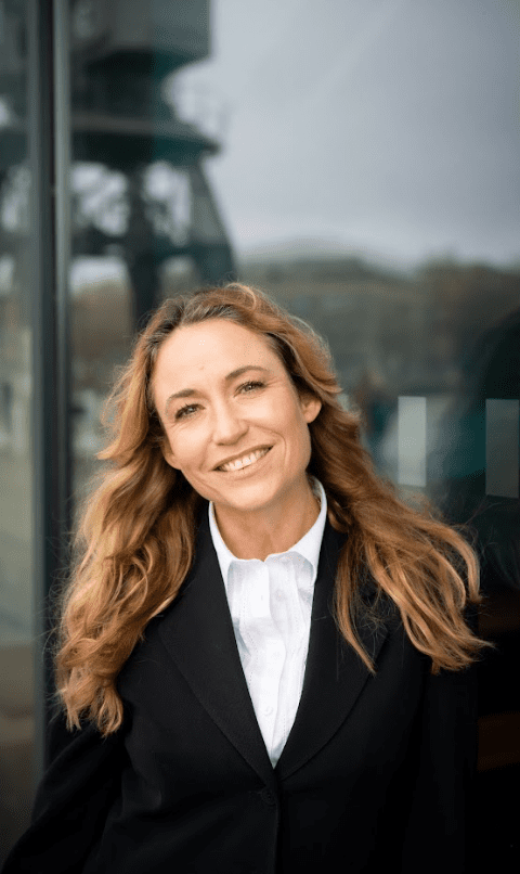 Woman wearing a white shirt and black blazer smiling at the camera