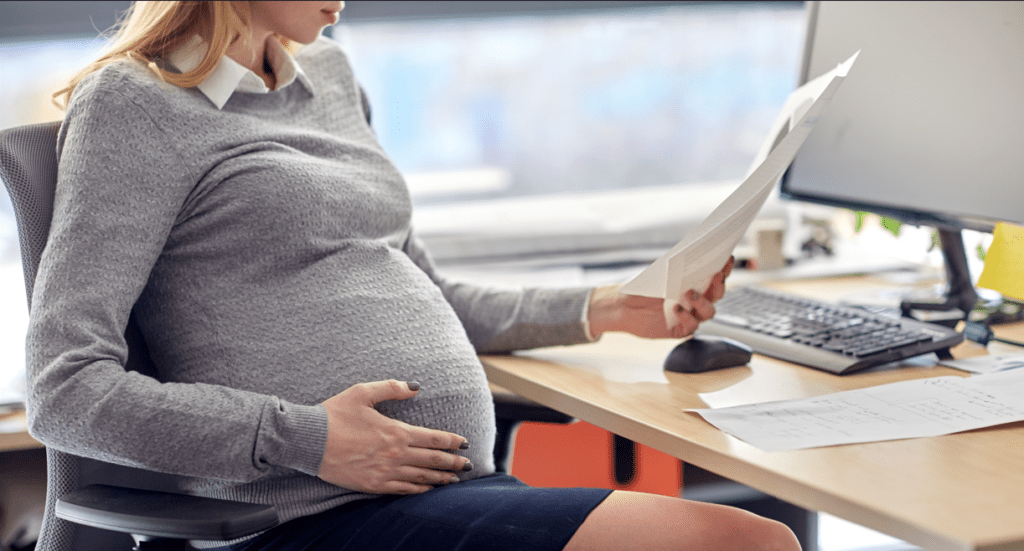 pregnant businesswoman reading papers at office
