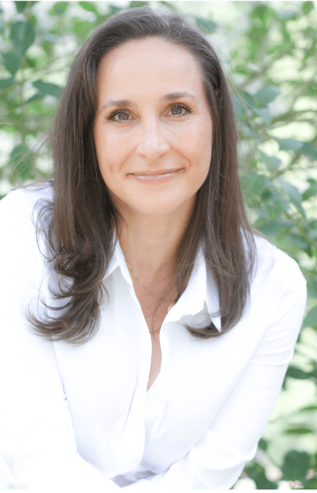 Woman wearing white button up, short brown hair, smiling at camera