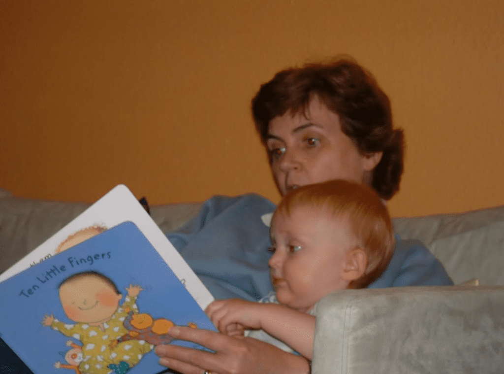 picture of a young grace with her mum, sat on the sofa reading a book