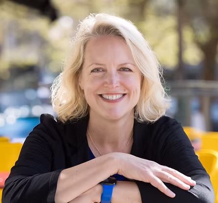Woman with short blonde hair, black shirt, smiling at camera 